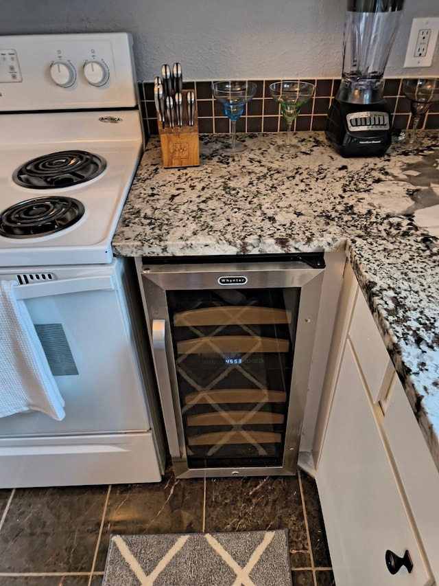 interior details featuring white cabinets, white electric range oven, bar, beverage cooler, and backsplash