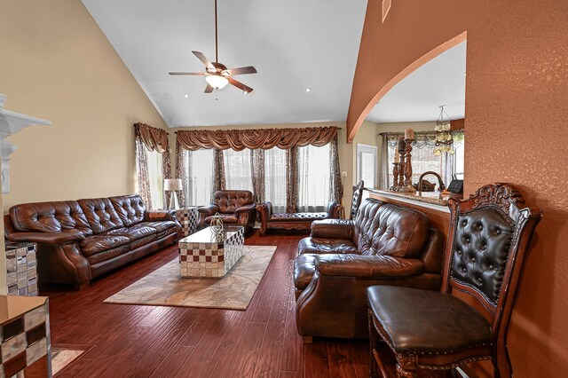 living room featuring ceiling fan with notable chandelier, lofted ceiling, and dark wood-type flooring