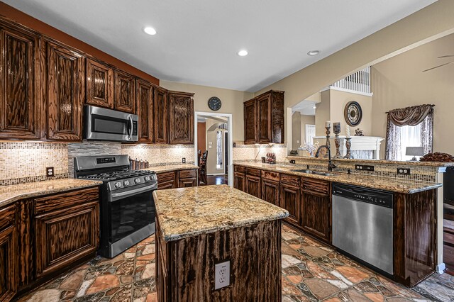 kitchen featuring stainless steel appliances, kitchen peninsula, sink, and a center island