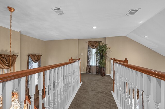 corridor featuring lofted ceiling and dark colored carpet