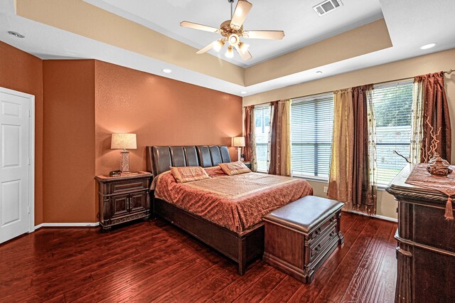 bedroom featuring ceiling fan, a tray ceiling, and dark hardwood / wood-style floors