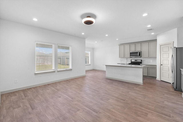 kitchen with gray cabinets, recessed lighting, an island with sink, and stainless steel appliances