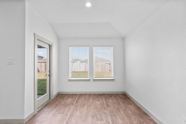 spare room with lofted ceiling, light hardwood / wood-style floors, and a healthy amount of sunlight