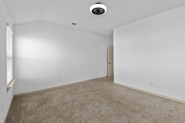 carpeted spare room featuring baseboards, lofted ceiling, and visible vents