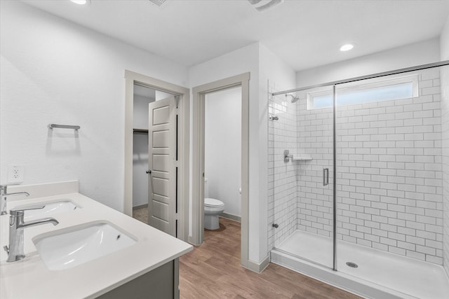bathroom featuring a shower stall, wood finished floors, a sink, and toilet