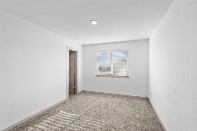 carpeted empty room featuring baseboards
