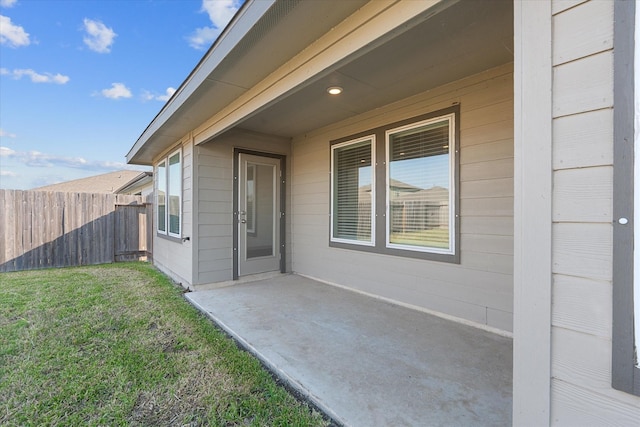 entrance to property featuring a yard, a patio area, and fence