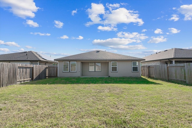 back of house with a yard and a fenced backyard