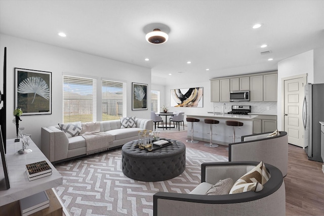 living room featuring visible vents, light wood-style flooring, and recessed lighting