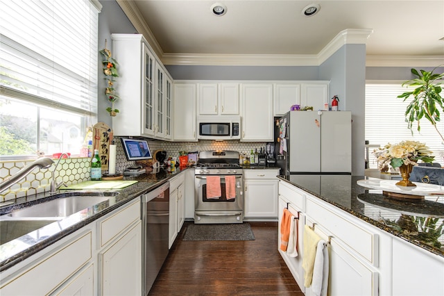 kitchen with dark hardwood / wood-style floors, dark stone countertops, crown molding, white cabinetry, and appliances with stainless steel finishes