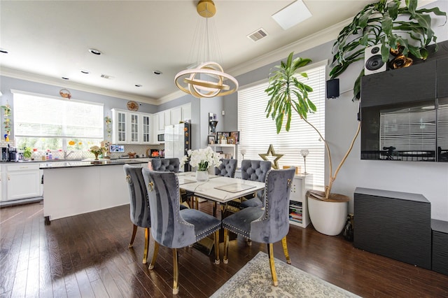 dining space with dark wood-type flooring, a chandelier, and crown molding