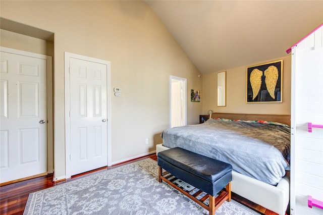 bedroom with wood finished floors, high vaulted ceiling, and baseboards