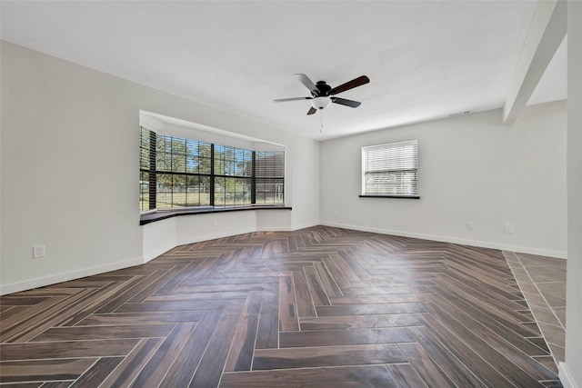 empty room featuring beamed ceiling, dark parquet flooring, and ceiling fan