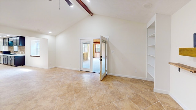 unfurnished living room with lofted ceiling with beams, ceiling fan, and sink