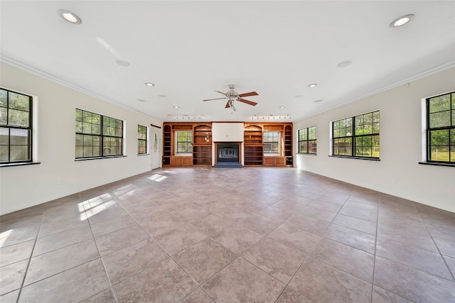 unfurnished living room with ceiling fan, ornamental molding, and a wealth of natural light