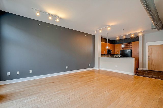 unfurnished living room featuring rail lighting and light wood-type flooring