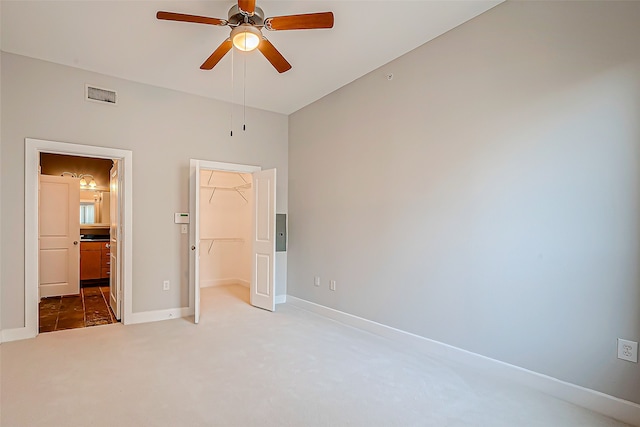 unfurnished bedroom with carpet, ceiling fan, vaulted ceiling, a closet, and a walk in closet