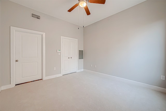 spare room with ceiling fan, electric panel, and light colored carpet