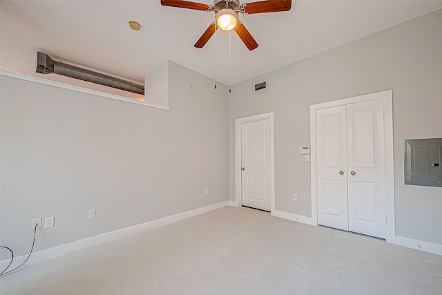 unfurnished bedroom featuring a closet, electric panel, light colored carpet, and ceiling fan