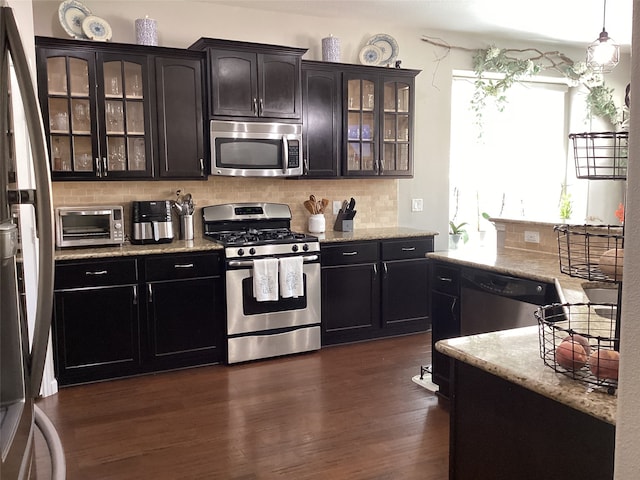 kitchen featuring light stone countertops, stainless steel appliances, dark wood-type flooring, pendant lighting, and backsplash