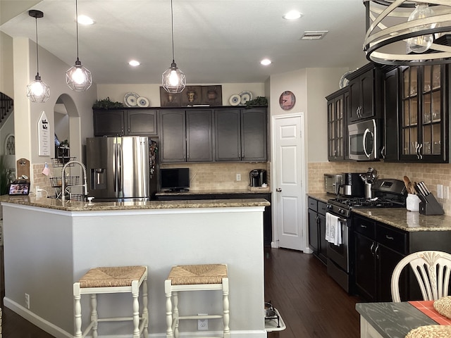 kitchen featuring pendant lighting, appliances with stainless steel finishes, dark hardwood / wood-style flooring, and decorative backsplash