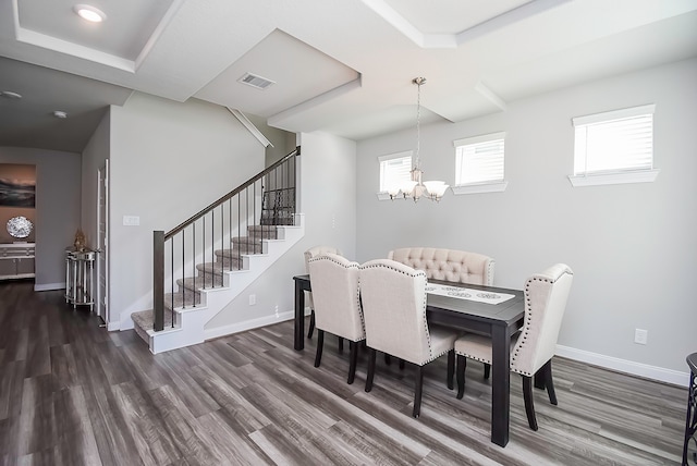 dining room with an inviting chandelier, a tray ceiling, and dark wood-type flooring