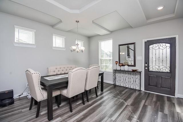 dining area with a notable chandelier, dark hardwood / wood-style floors, a raised ceiling, and a wealth of natural light