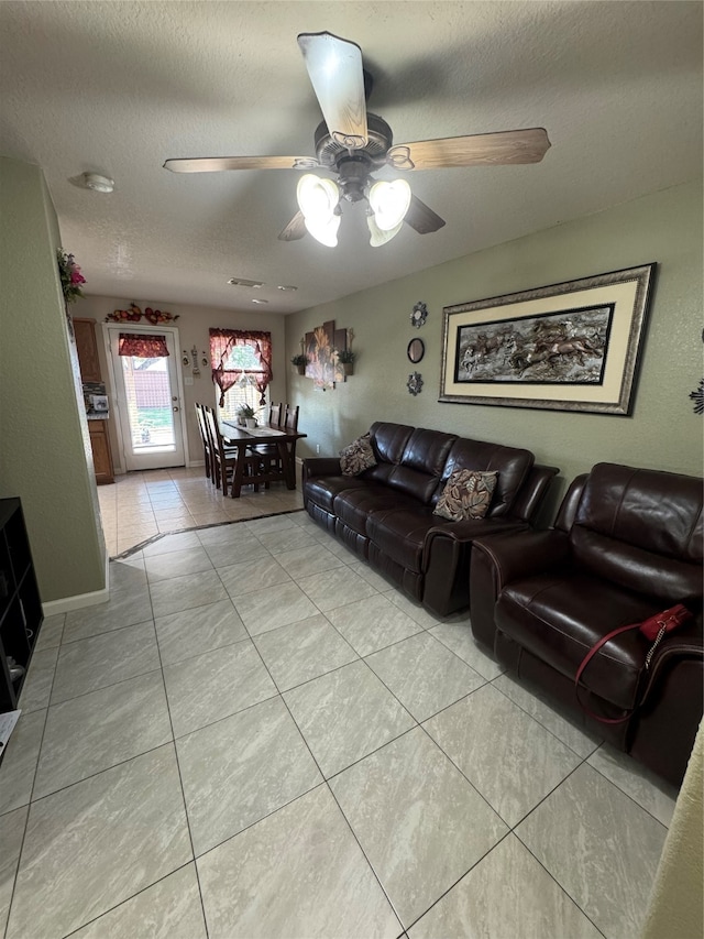 tiled living room with ceiling fan and a textured ceiling