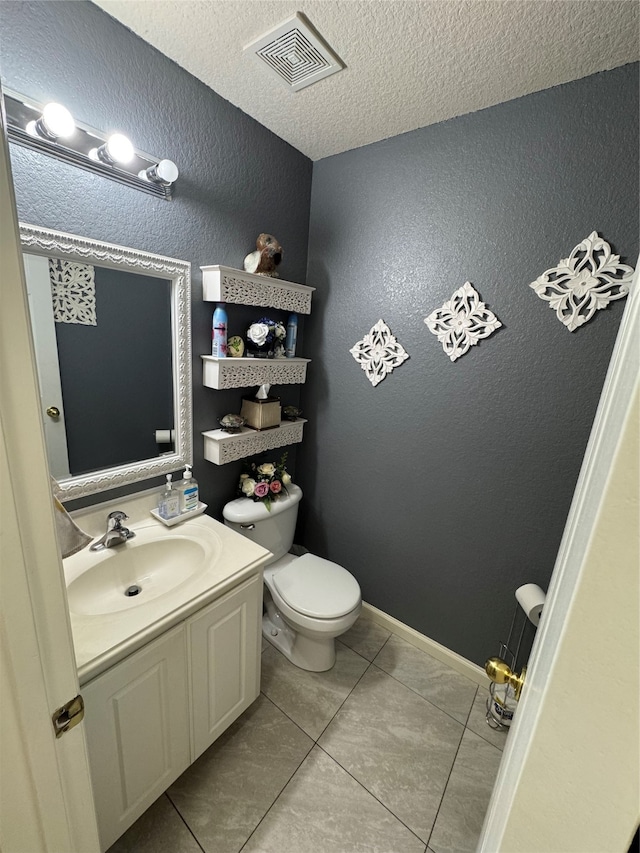 bathroom with a textured ceiling, tile patterned floors, vanity, and toilet