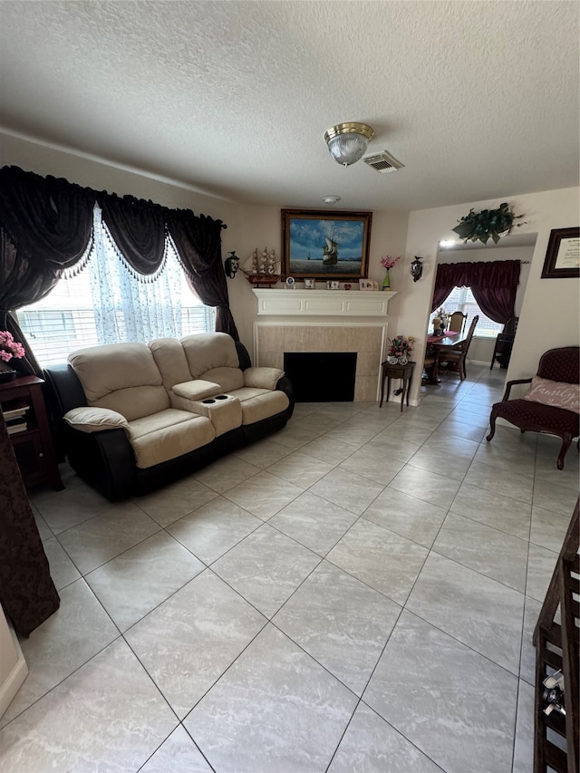 living room with a textured ceiling, light tile patterned floors, and a tile fireplace