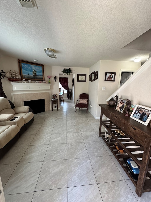 living room with a tile fireplace, tile patterned floors, and a textured ceiling