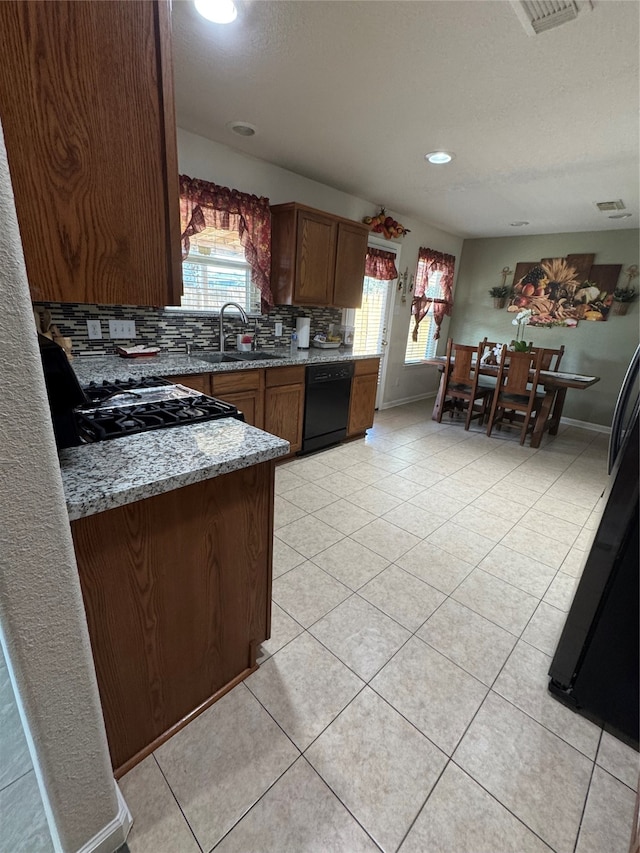 kitchen featuring light stone counters, sink, backsplash, black appliances, and light tile patterned floors