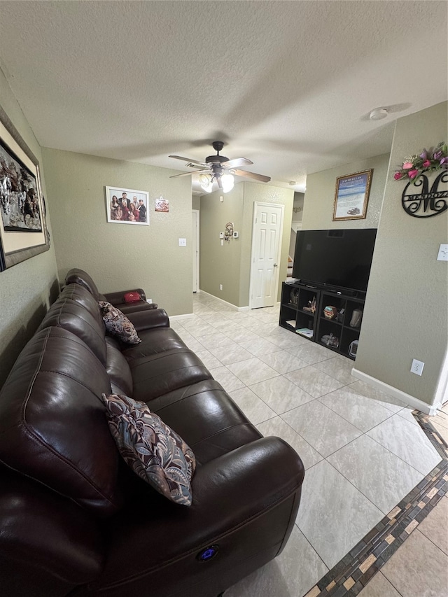 living room with light tile patterned flooring, ceiling fan, and a textured ceiling