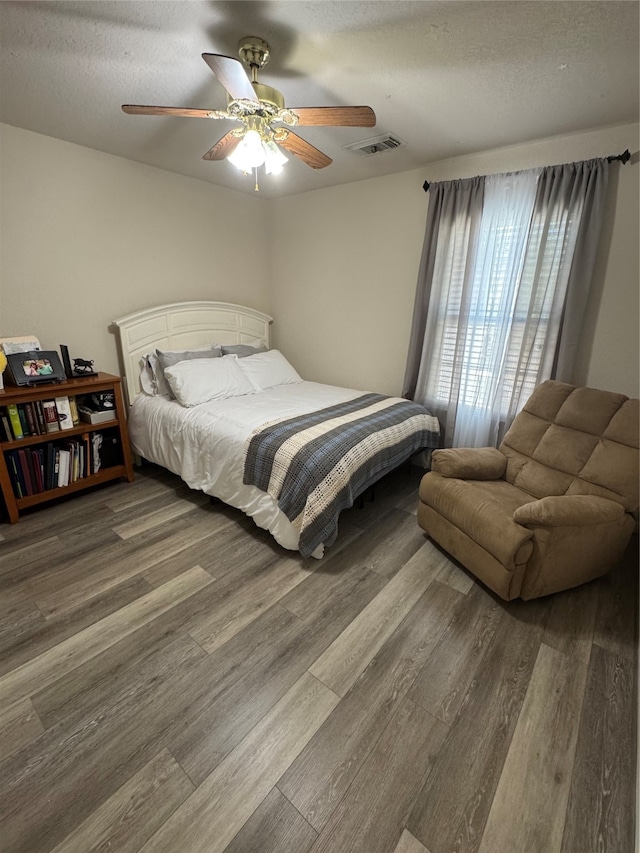 bedroom with ceiling fan, hardwood / wood-style flooring, and a textured ceiling