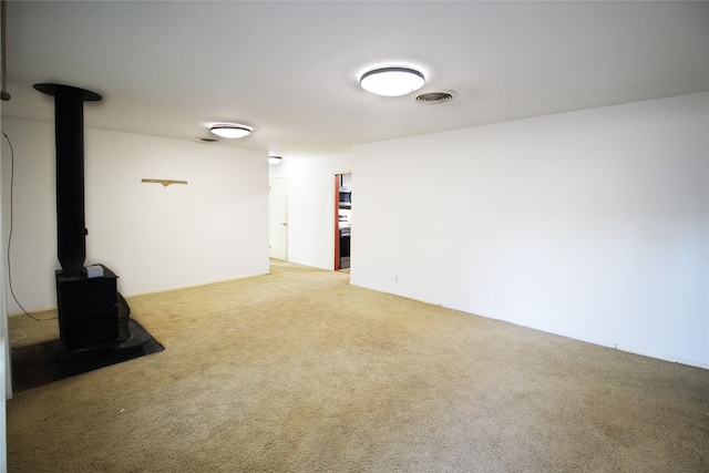 basement featuring a wood stove and light carpet