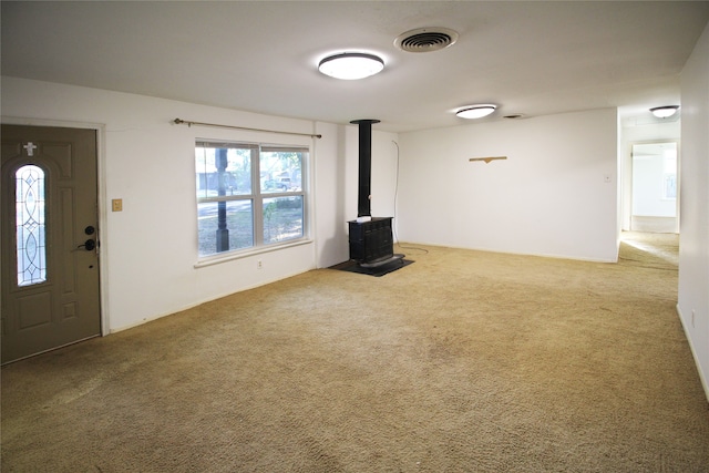 unfurnished living room featuring carpet and a wood stove