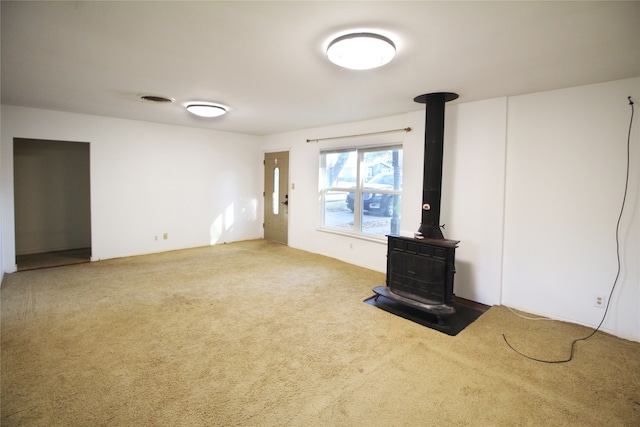 unfurnished living room with a wood stove and carpet flooring