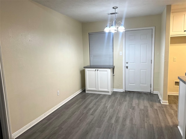 unfurnished dining area featuring dark hardwood / wood-style floors and a chandelier