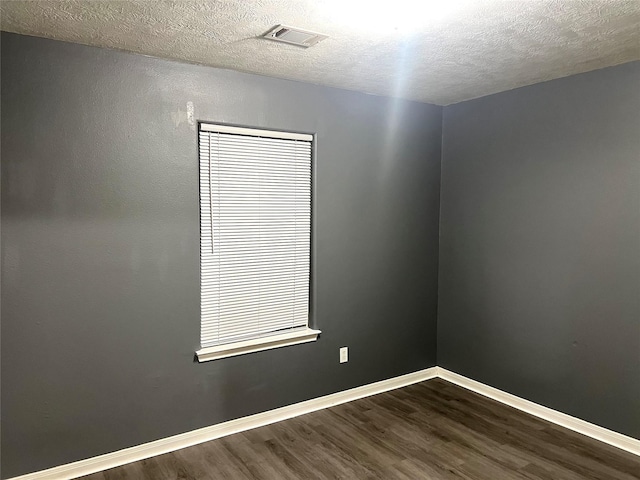 empty room with hardwood / wood-style flooring and a textured ceiling