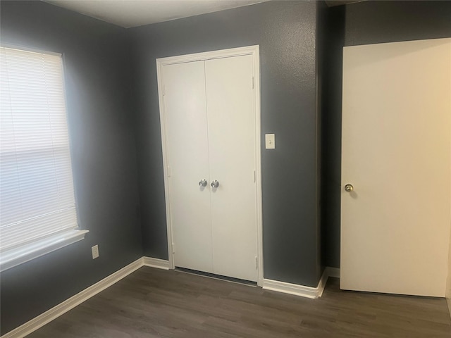 unfurnished bedroom with multiple windows, dark hardwood / wood-style floors, and a closet