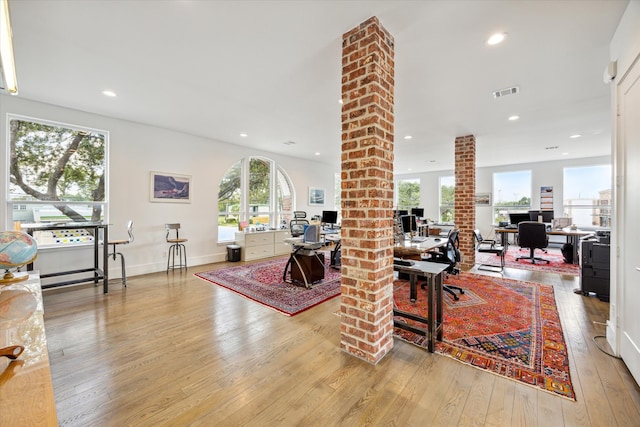 living room with decorative columns, a wealth of natural light, and light hardwood / wood-style flooring