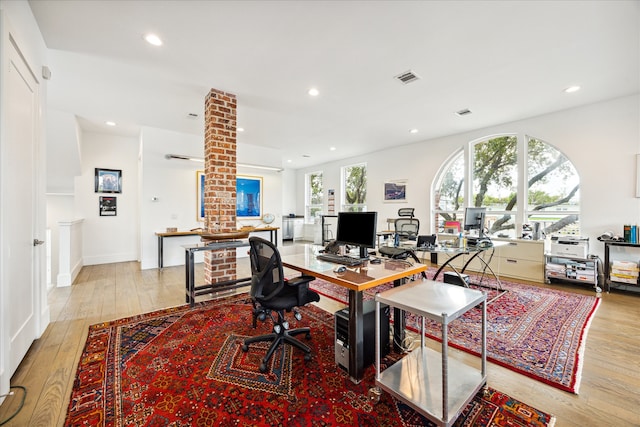 home office with ornate columns and light hardwood / wood-style floors