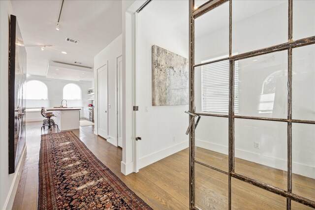 hall with hardwood / wood-style flooring and sink