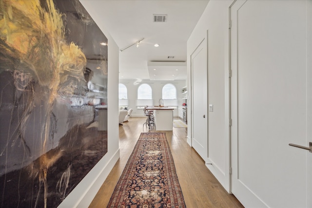 hallway with sink and light hardwood / wood-style flooring