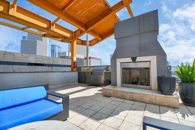 view of patio / terrace with grilling area, an outdoor kitchen, and a tiled fireplace