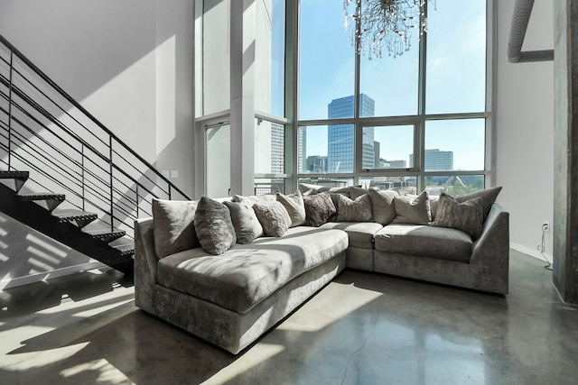 living room featuring a healthy amount of sunlight, expansive windows, a towering ceiling, and an inviting chandelier