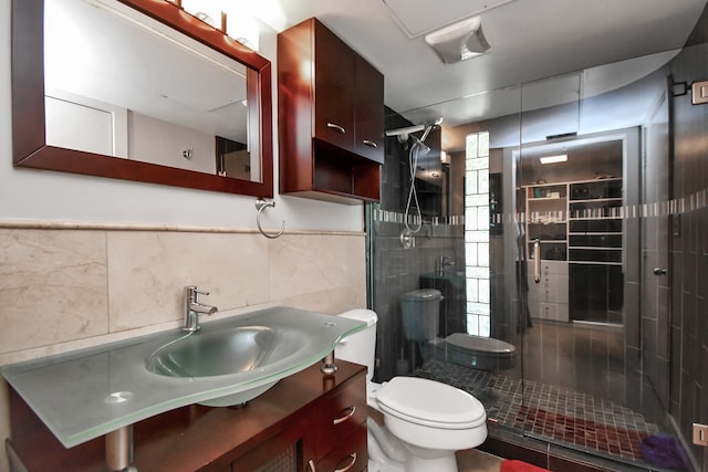 bathroom with vanity, tile walls, toilet, and an enclosed shower