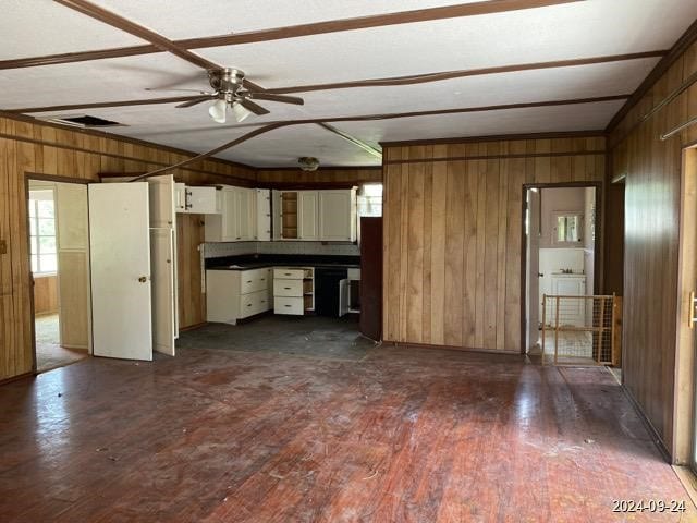 kitchen with ceiling fan, white cabinets, wood walls, and dark hardwood / wood-style floors