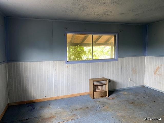 empty room with a textured ceiling, concrete flooring, and baseboards