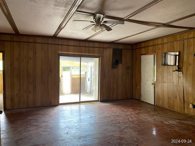 interior space with wooden walls, ceiling fan, and a textured ceiling